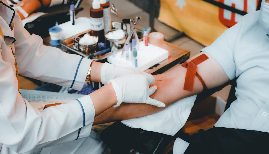 Healthcare worker in gloves gently collecting a blood sample from a patient's arm