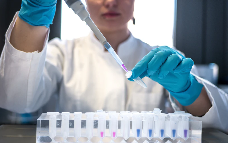 Lab technician using a pipette with test tubes